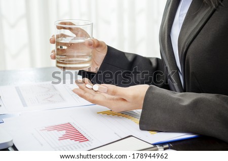 Business person holding medicine and glass of water