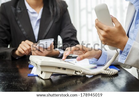 Office worker using telephone and mobile phone
