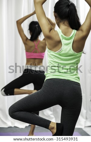 close up of women doing yoga pose while standing on one leg
