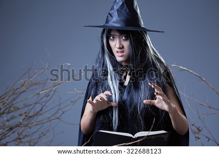 young witch casting a spell and holding a book