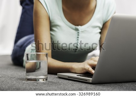 young woman laying on the floor while using her laptop