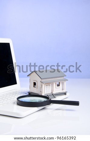 a model house, a computer and a lens with blue background