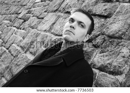 Man leans against stone wall.