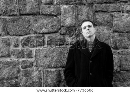Man leans against stone wall.