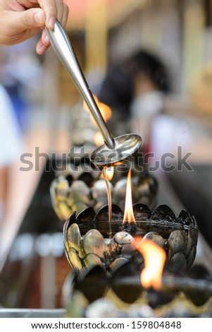 Oil filling in Thai style metal candle in Thai temple, Chiang Mai, Thailand