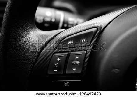 Close up of steering wheel of modern car. Volume and telephone command with cockpit background , black and white
