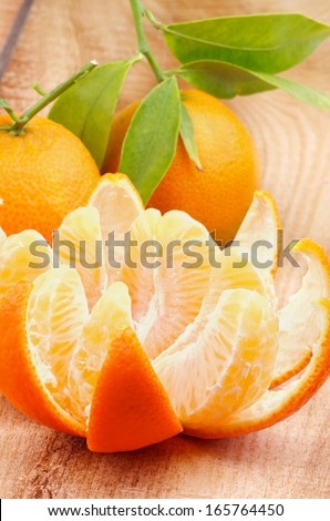 Fresh Ripe Tangerine Full Body with Leafs and  Segments with Citrus Peel closeup on Wooden background