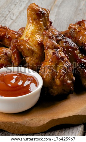Chicken Legs and Wings Barbecue with Ketchup on Wooden Plate closeup