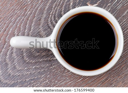 Soy Sauce in White Gravy Boat isolated on Wooden background. Top View