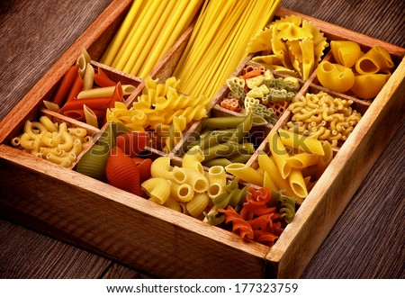 Various Raw Dry Pasta in Wooden Box Cross Section on Rustic Wooden background