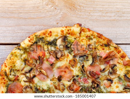 Part of Freshly Baked Pizza with Edible Mushrooms, Bacon, Cheese and Spinach Sauce closeup on Wooden background. Top View