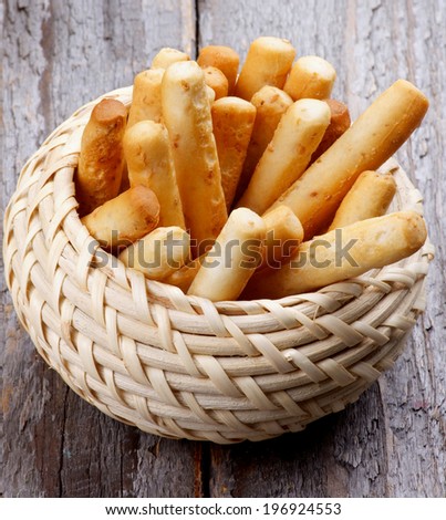 Bread Sticks with Sesame Seeds in Wicker Bowl isolated on Rustic Wooden background