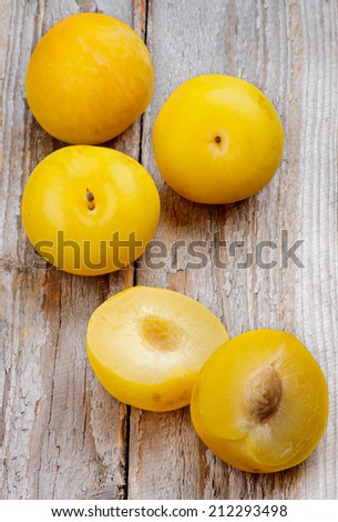 Arrangement of Ripe Sweet Yellow Plums Full Body and Halves isolated on Rustic Wooden background
