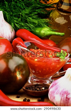 Bruschetta Sauce in Glass Gravy Boat with Black Tomatoes, Garlic, Chili Peppers, Dill and Olive Oil in Glass Bottle closeup