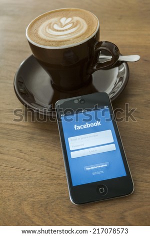 THAILAND - SEPTEMBER 05, 2014: Facebook application login screen on ipod apple product with morning coffee and wood desk background.
