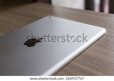 CHIANG MAI, THAILAND - OCTOBER 21, 2014: Logo of Apple in back Apple iPad air on wood desk.