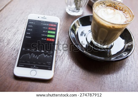 CHIANG MAI, THAILAND - APRIL 22, 2015: iPhone 6 with application Stocks of Apple on the screen in coffee shop cafe. iPhone 6 was created and developed by the Apple inc.