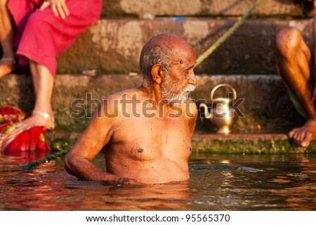 VARANASI, INDIA - APRIL 24: Unidentified man taking ritual bath in the river Ganga on April 24, 2011 in the holy city of Varanasi, India. The holy ritual bath is held every day.