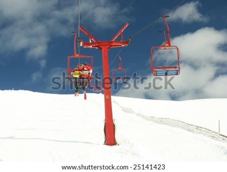 Young couple hugged in chair lift over the slopes