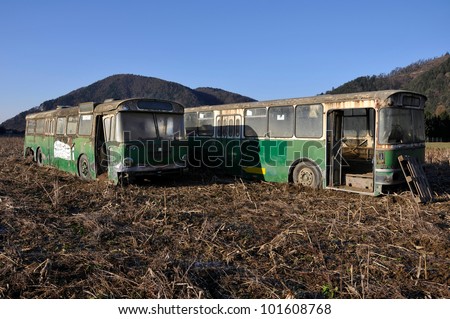 two discarded buses in the field