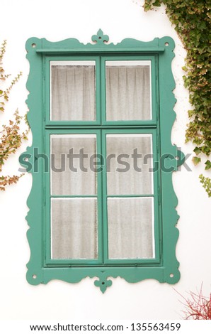 squiggled emerald lacquered wooden window frame surrounded with ivy