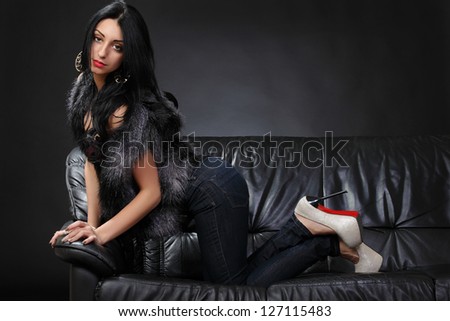 Beautiful brunette lying on a leather couch