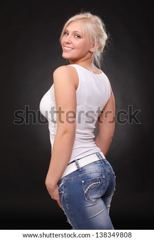 a young blonde wearing jeans and a tank top. on a black background