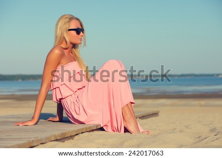 girl in a ping dress and sunglasses on background of sky