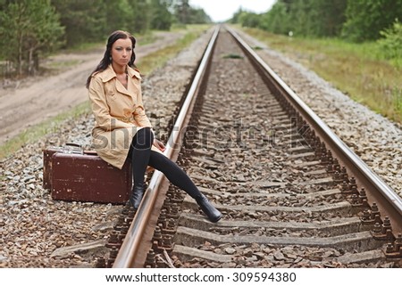 Young woman with a suitcase on the rails