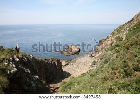 View of rocky coast with diving boat and wanderer, from Kullaberg in Sweden.