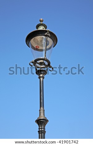 Old fashioned wrought iron street lamp in Nyhavn, Copenhagen, Denmark - on a blue sky. Originally a gas lamp, now electric.