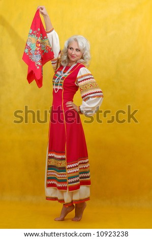 Russian woman in a folk russian dress waves a scarf on yellow background
