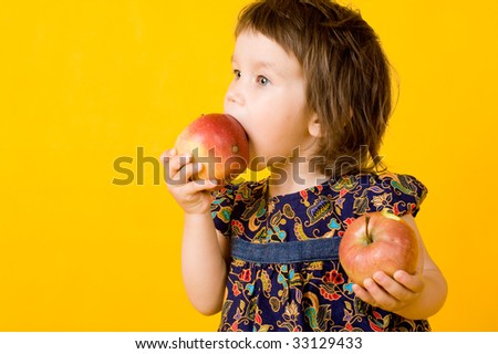 Little girl with two apple isolated on yellow  background