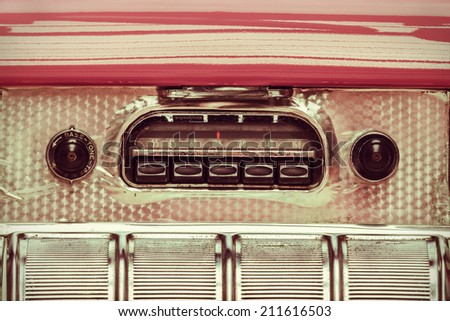 Retro styled image of an old car radio inside a pink classic car