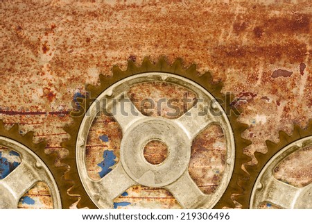 Three ancient cog wheels against a rusty background