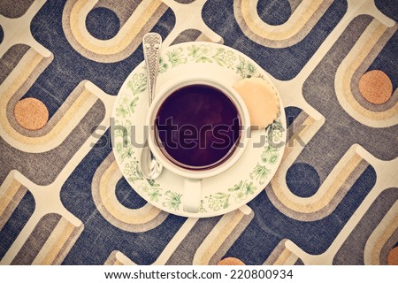 Retro styled image of a cup of coffee on a table with a vintage table cloth