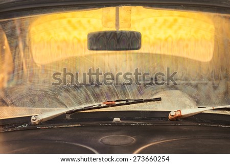 Front window of a dirty old black car with rusted screen wipers