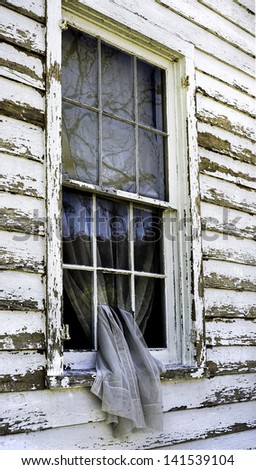 A curtain slips through the broken window of an abandoned home near Blenheim, New York.