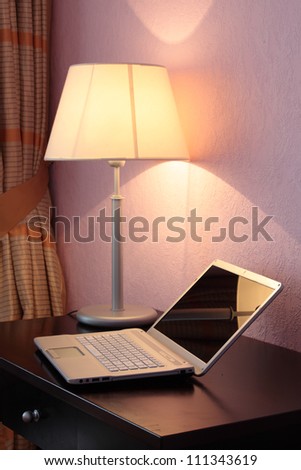 Laptop on a table under desk lamp
