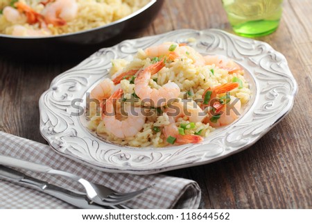 Risotto with shrimps and green onion on a rustic table