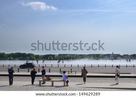 BORDEAUX, FRANCE - JUNE 27: People walk on the water mirror on the Place de la Bourse in Bordeaux, France on June 27, 2013. Opened in 2006, the water mirror is the largest in the world with 3450 sq. m