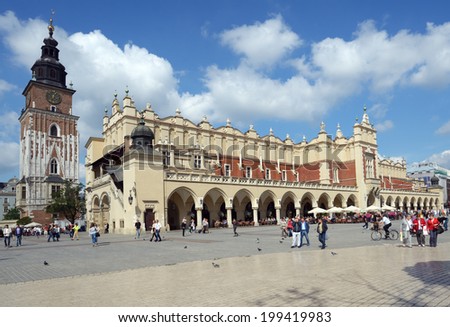 KRAKOW, POLAND - SEPTEMBER 15, 2013: People on the Main Market Square near Sukiennice, Cloth Hall, and the Town Hall tower. The Cloth Hall was built in XIV century, and now hosts souvenir shops