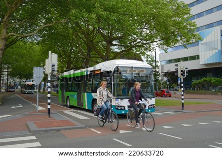 DORDRECHT, NETHERLANDS - JUNE 23, 2013: Women on bikes and the public bus on the Stationsweg street. The Maastricht University calls the bicycle an element of the real Dutch life
