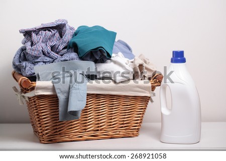 Dirty clothes in the laundry basket and a bottle of detergent