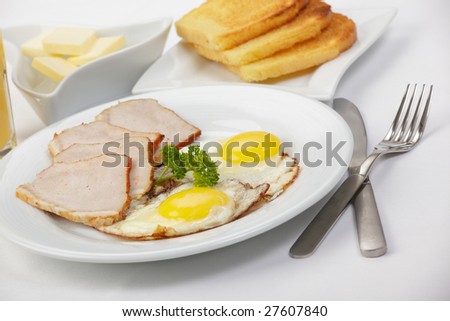 American breakfast with fried eggs, bacon, toasts, butter, and juice