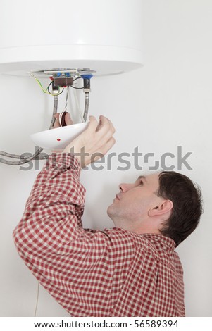 Worker connecting a water heater to the electric network