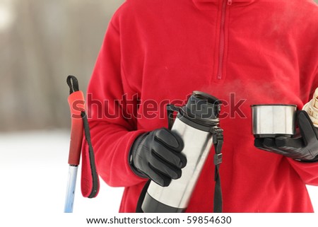 Cross-country skier pouring hot drink from thermos to a cup