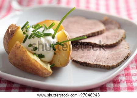 Roast beef and baked potato with sour cream and green onion
