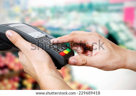 Hand with credit card swipe through terminal for sale in supermarket