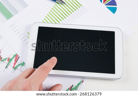 Businessman working with digital tablet. Report charts on desk